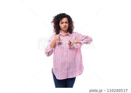 young curly brunette model woman dressed in a pink striped shirt shows like and dislike 110280517