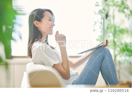 リビングでパソコンを見る若い女性 110280518