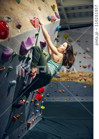 Young sportive, muscular woman, bouldering instructor training, practicing indoors, climbing wall 110281957