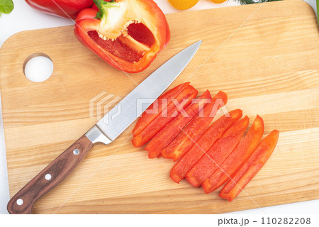 Close-up of slicing red sweet pepper and kitchen knife on cutting board. 110282208