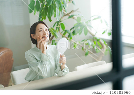 鏡を持ち肌のチェックをする女性 110283960
