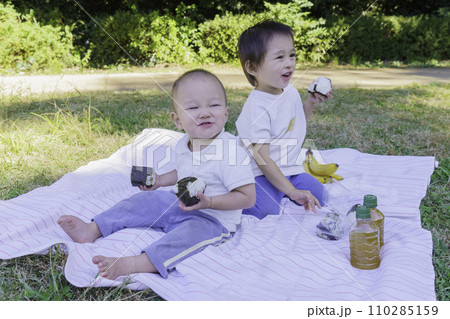 公園でおにぎりを食べる男の子の兄弟 110285159