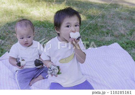 公園でおにぎりを食べる男の子の兄弟 110285161