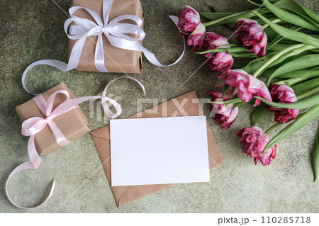 A bouquet of tulips, gifts and mock up blank white paper card for text. Flat lay, top view. Place for text. Greeting card A bouquet of tulips, gifts and mock up blank white paper card for text. Flat lay, top view. Place for text. Greeting card 110285718