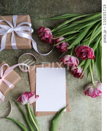 A bouquet of tulips, gifts and mock up blank white paper card for text. Flat lay, top view. Place for text. Greeting card 110285719