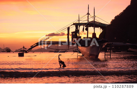 Traditional philippine boat bangka at sunset time. Beautiful sunset with silhouettes of philippine boats in El Nido, Palawan island, Philippines. Orange sky sunset paradise beach. Traditional philippine boat bangka at sunset time. Beautiful sunset with silhouettes of philippine boats in El Nido, Palawan island, Philippines. Orange sky sunset paradise beach. 110287889