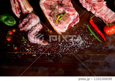 Set of raw meat. Pork meat on black stone background with spices and herbs. Top view. Rustic style. 110288690