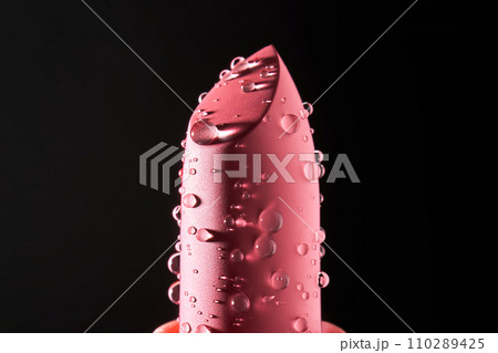 Red lipstick with water drops on a dark background. Red lipstick with water drops on a dark background. 110289425