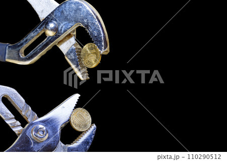 Allegory of the global financial crisis - Iron 10 rubles coin (written ten rubles, Bank of Russia in the Russian) in the grip of economic crisis, on a black background. Finance and business concept 110290512