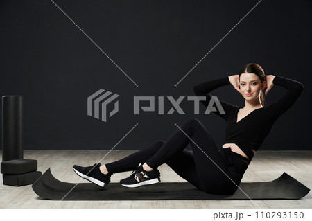 Fit young woman in sportswear working on core, during exercise session on floor of gym. Side view of caucasian sportswoman keeping hands behind head, doing abdominal twist for core. Sport concept. Fit young woman in sportswear working on core, during exercise session on floor of gym. Side view of caucasian sportswoman keeping hands behind head, doing abdominal twist for core. Sport concept. 110293150