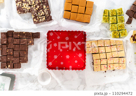 Flat lay. Packaging a homemade variety of fudge for Christmas food gifts into tin boxes. Flat lay. Packaging a homemade variety of fudge for Christmas food gifts into tin boxes. 110294472