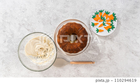 Flat lay. Icing freshly baked carrot bundt cake with cream cheese buttercream. 110294619