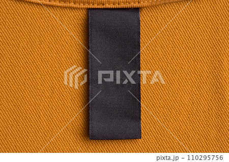 Blank black laundry care clothes label on yellow fabric texture background 110295756