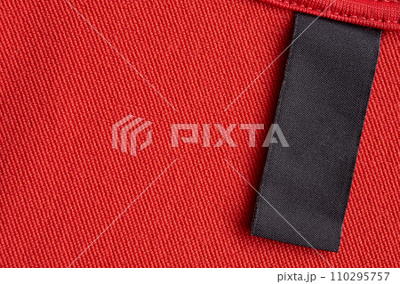 Blank black laundry care clothes label on red fabric texture background Blank black laundry care clothes label on red fabric texture background 110295757