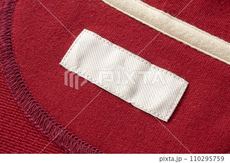 Blank white laundry care clothes label on red fabric texture background 110295759