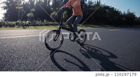 Riding folding bike on sunny seaside road 110297179