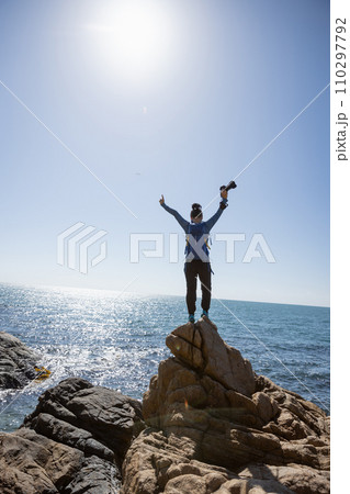 Woman photographer enjoy the view on sunrise seaside rocks Woman photographer enjoy the view on sunrise seaside rocks 110297792