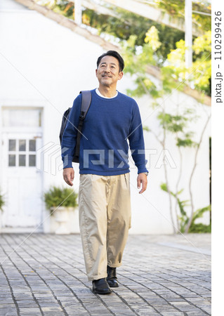 バックパックを持って歩く50代半ばの男性　 110299426