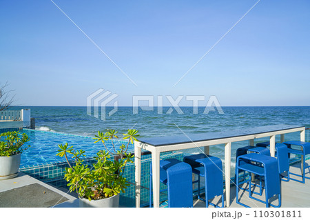 desk and bar stool near swimming pool with sea background 110301811