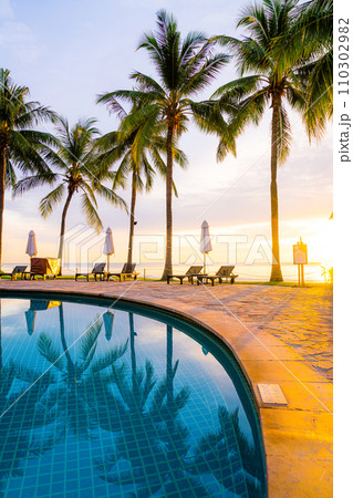 Umbrella and chair around swimming pool in hotel resort with sunrise in morning 110302982