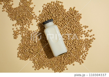 An unlabeled bottle filled with milk displayed on a pile of soybeans. Top view. Concept of natural ingredients for branding mockup design An unlabeled bottle filled with milk displayed on a pile of soybeans. Top view. Concept of natural ingredients for branding mockup design 110304337