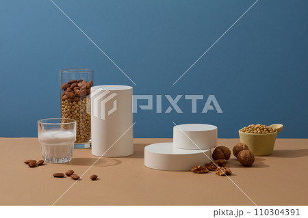 Minimal scene with geometric shaped podiums displayed with a cup of milk, a bowl of soybeans, almonds and walnuts. Stage showcase on pedestal display Minimal scene with geometric shaped podiums displayed with a cup of milk, a bowl of soybeans, almonds and walnuts. Stage showcase on pedestal display 110304391