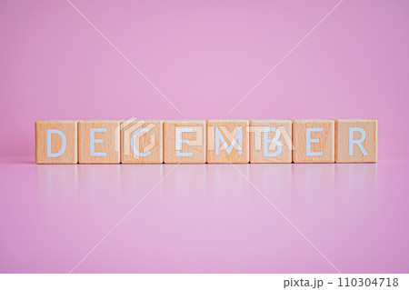 Wooden blocks form the text "DECEMBER" against a pink background. 110304718
