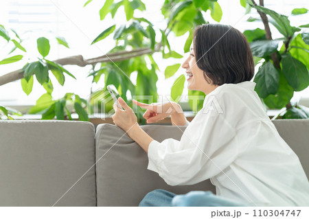 ソファーに座ってスマホを見る女性 ソファーに座ってスマホを見る女性 110304747