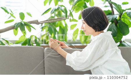 ソファーに座ってスマホを見る女性 110304752