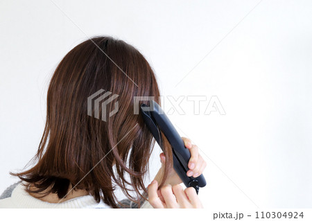 ストレートアイロンを使う女性　ヘアセット 110304924