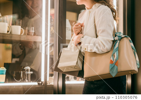 ショーウィンドウの商品を見てショッピングを楽しむビジネスウーマン 110305076