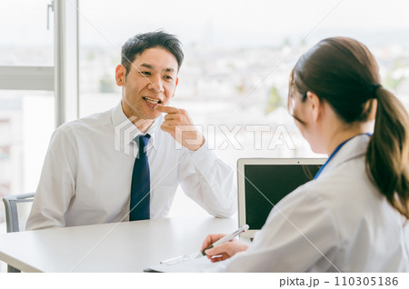 歯周病を医師に相談するビジネスマン（虫歯・口腔ケア・矯正・歯並び） 110305186