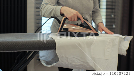 Woman using iron with steam mode for wrinkled clothes. Home Routine Housekeeping. 110307225