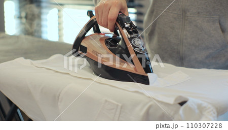 Woman using iron with steam mode for wrinkled clothes. Home Routine Housekeeping. Woman using iron with steam mode for wrinkled clothes. Home Routine Housekeeping. 110307228