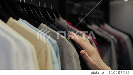 Woman in the shop looks through the male clothes, which are hanging on the racks. Home closet or wardrobe. Woman in the shop looks through the male clothes, which are hanging on the racks. Home closet or wardrobe. 110307312