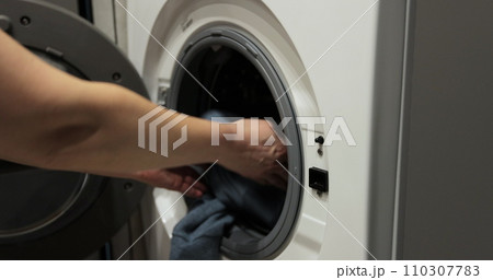 Woman hands putting dirty clothes into washing machine. Clothes cleaning, laundry service. Woman hands putting dirty clothes into washing machine. Clothes cleaning, laundry service. 110307783