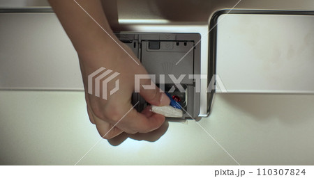 Close-up, top view. Woman putting an all in one detergent capsule pill into a dishwasher. 110307824