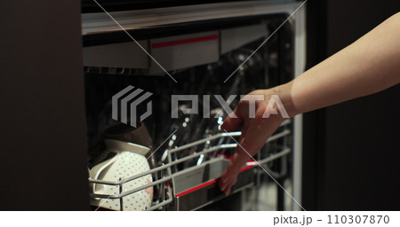 Woman puts dirty glasses in dishwasher machine. Housewife use modern appliance keep clean kitchen. Woman puts dirty glasses in dishwasher machine. Housewife use modern appliance keep clean kitchen. 110307870