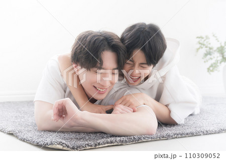 うつ伏せになりながら寝転がってはしゃぐカップル うつ伏せになりながら寝転がってはしゃぐカップル 110309052