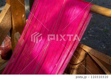 Close up of pink silk weaving on loom 110310310