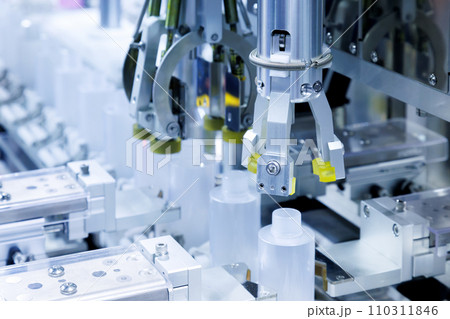 robot arm moving plastic bottle to conveyor belt of auto capping and labeling machine at cosmetic and skin care manufacturing. cosmetic industry and ai technology machinery concept. 110311846