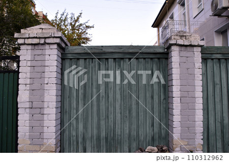 The background is made of green wooden boards. Brick and wooden fence. Old boards. 110312962