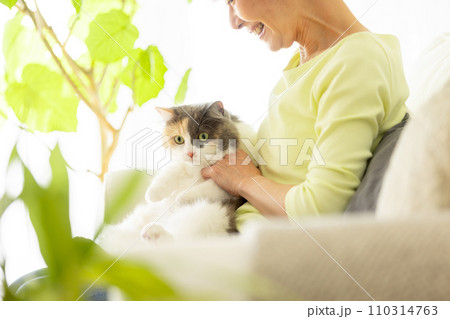 家で猫を抱っこする日本人シニア女性（猫・飼い主） 110314763