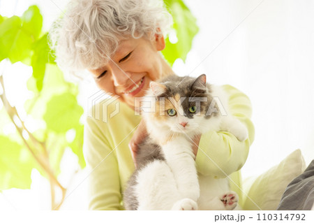 家で猫を抱っこする日本人シニア女性（猫・飼い主） 110314792