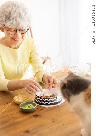 猫の餌を準備するシニア女性(猫・飼い主) 猫の餌を準備するシニア女性(猫・飼い主) 110315233