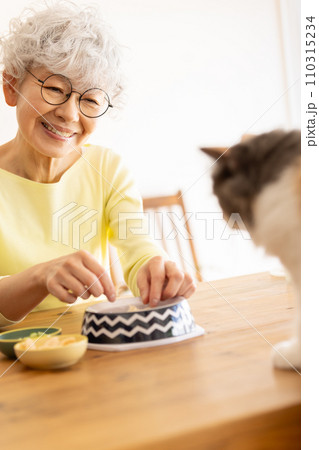 猫の餌を準備するシニア女性（猫・飼い主） 110315234