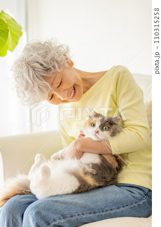 家で猫を抱っこする日本人シニア女性（猫・飼い主） 110315258