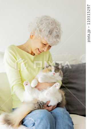 家で猫を抱っこする日本人シニア女性（猫・飼い主） 110315297