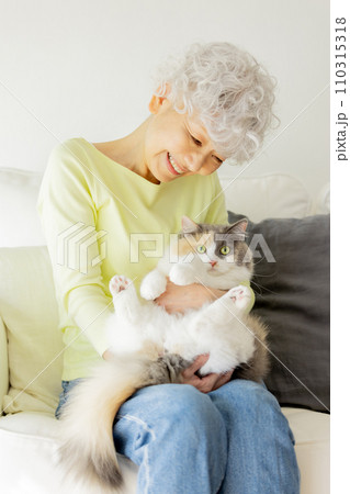 家で猫を抱っこする日本人シニア女性（猫・飼い主） 110315318