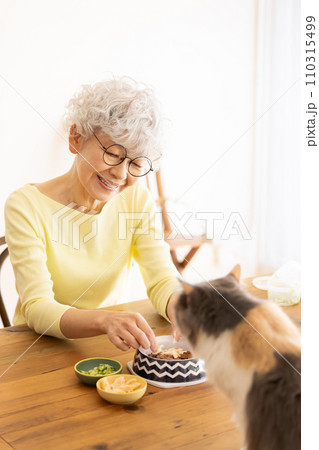猫の餌を準備するシニア女性（猫・飼い主） 110315499